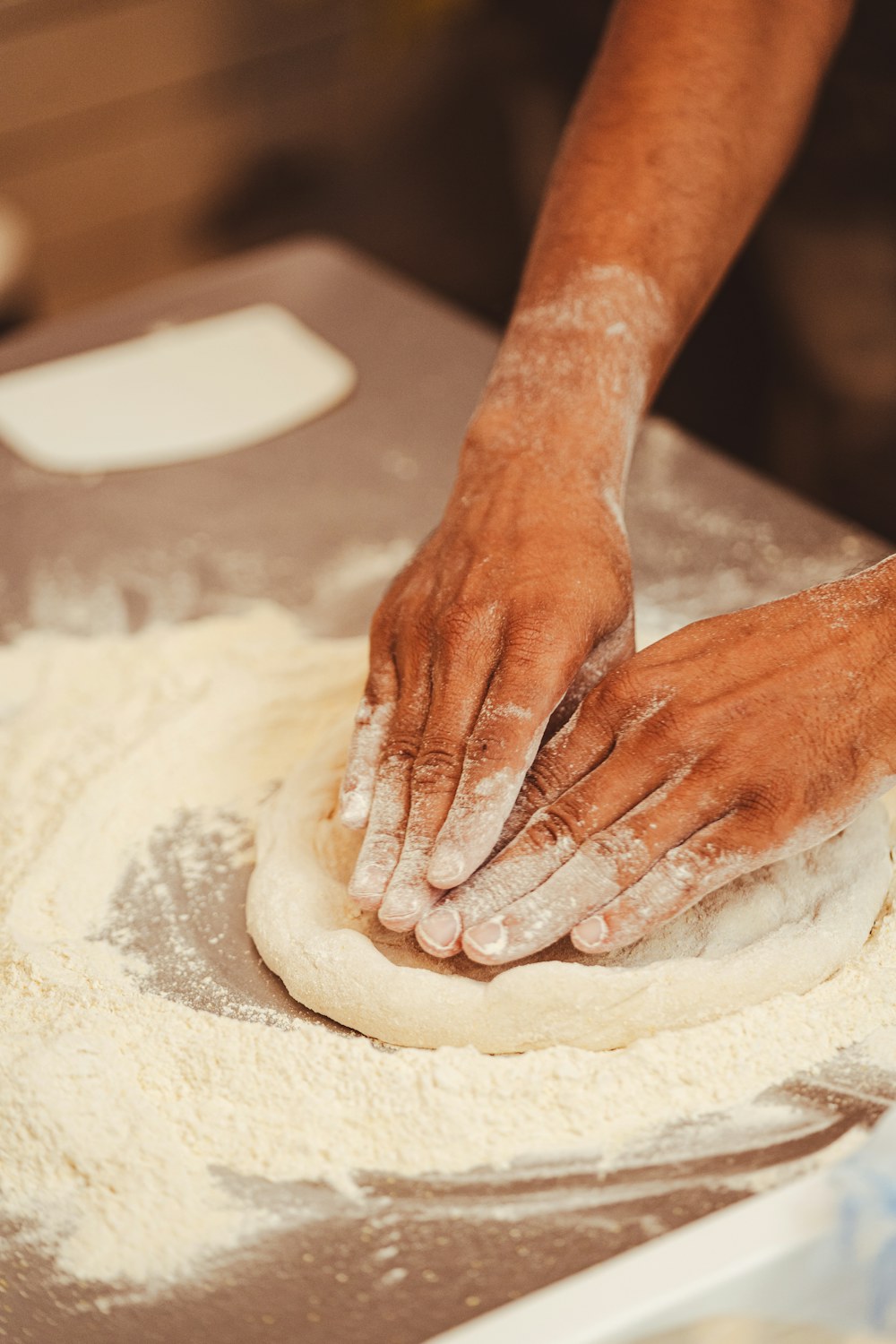 Flour-dusted hands shaping a round of pizza dough