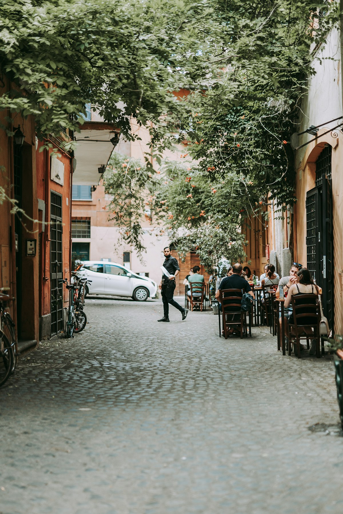 An ivy-covered lane with outdoor dining tables in Trastevere
